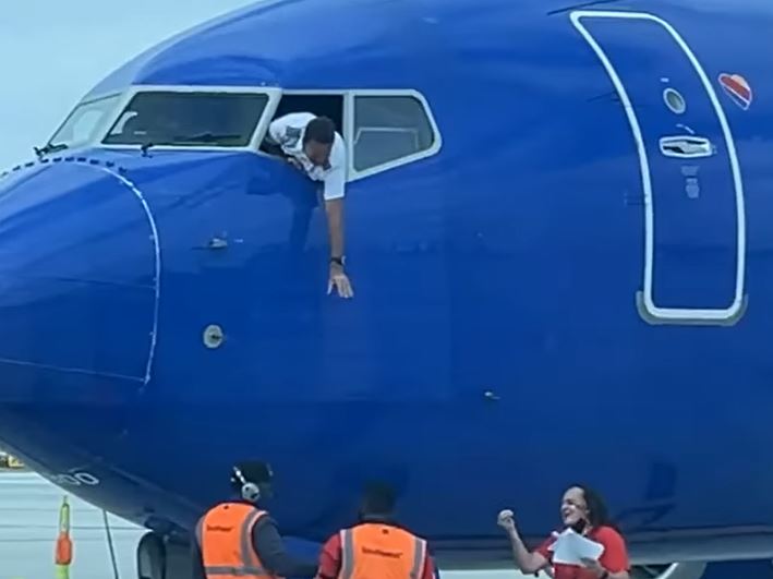 Piloti varet nga dritarja për të marrë telefonin e harruar të pasagjerit (VIDEO)